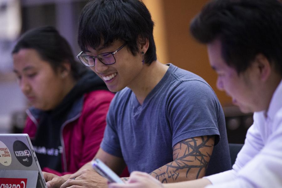 A student smiles while working on a computer.