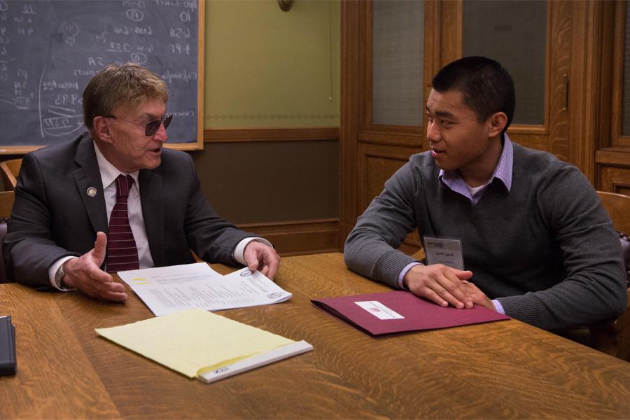 Two people talk around a table.