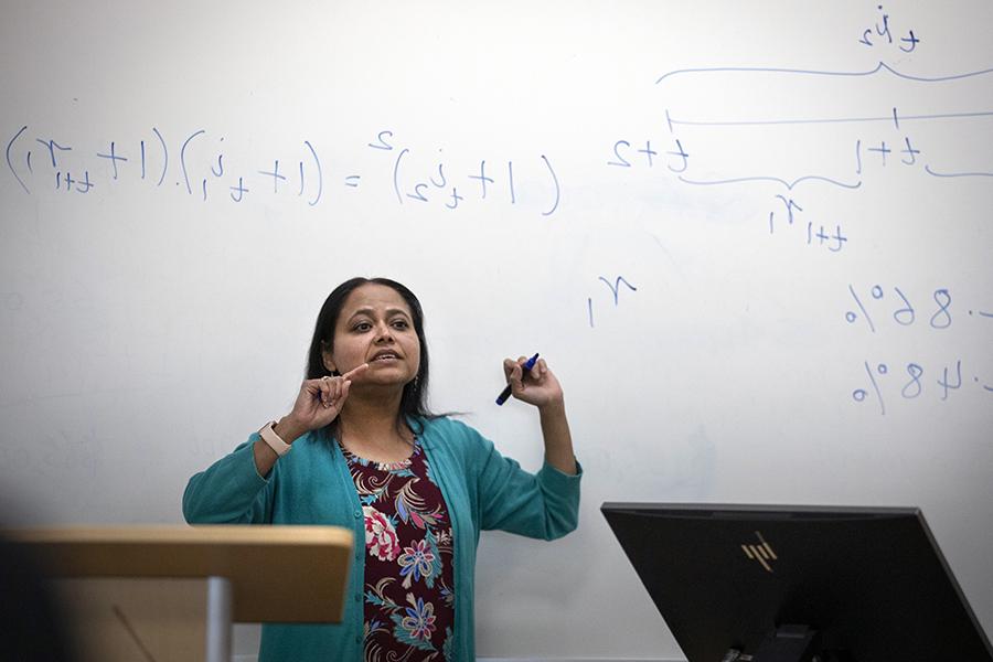 A faculty member teaches at the white board.