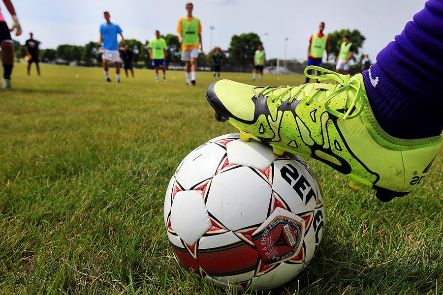 A yellow soccer cleat rests on a white and red soccer ball.