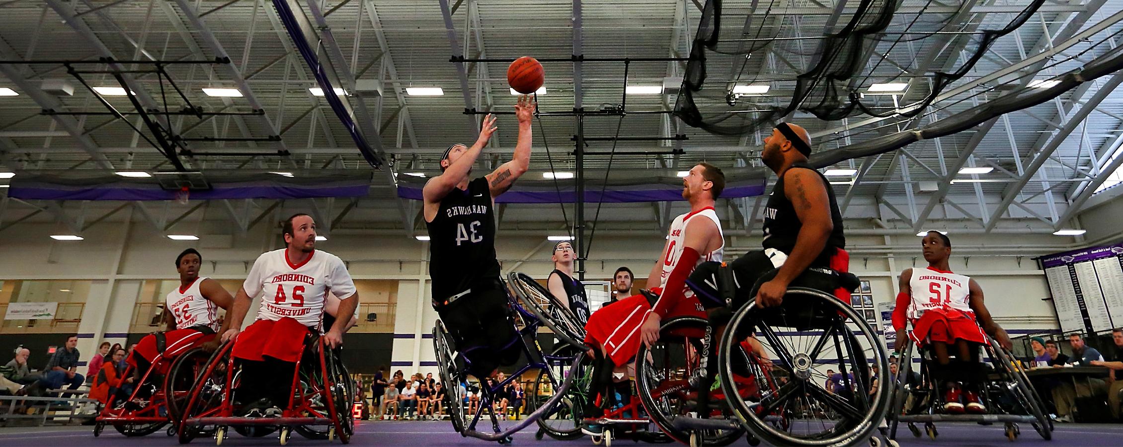 A Warhawk men's wheelchair basketball player shoots the ball.