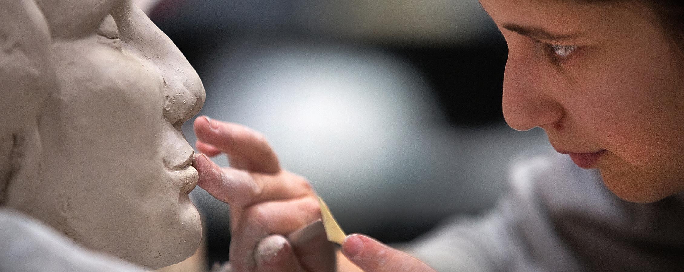 Person working on the face of a sculpture.