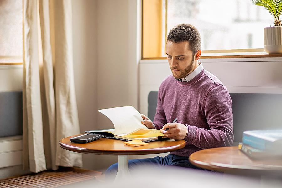 Man studying near cafe window with textbook