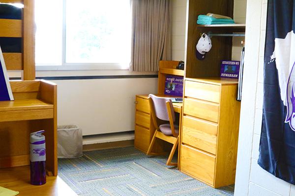 A dorm room where the beds are bunked, there is more free floor space in the room with this furniture arrangement.