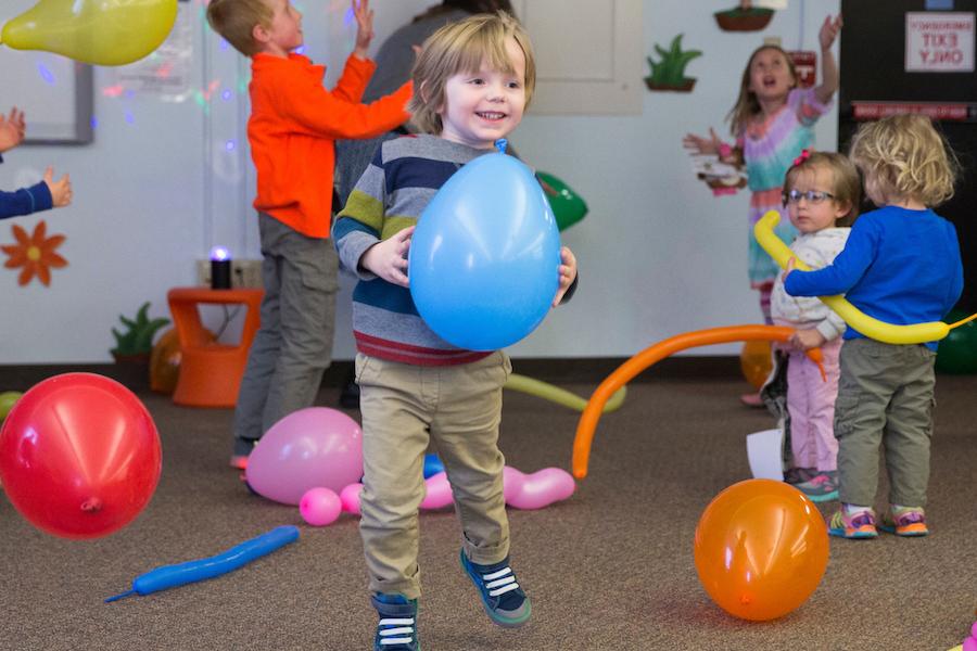 Children playing with balloons at Andersen Library stuffed animal sleep over event